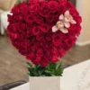 A heart-shaped arrangement featuring vibrant red roses and delicate orchids, symbolizing love and beauty.