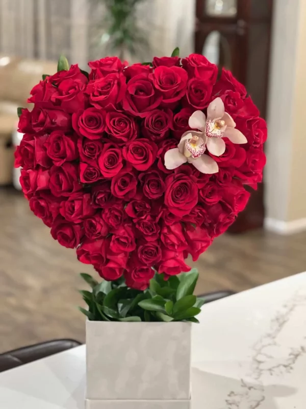 A heart-shaped arrangement featuring vibrant red roses and delicate orchids, symbolizing love and beauty.