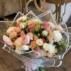 A vibrant bouquet of assorted flowers elegantly arranged inside a clear plastic bag, showcasing their natural beauty.