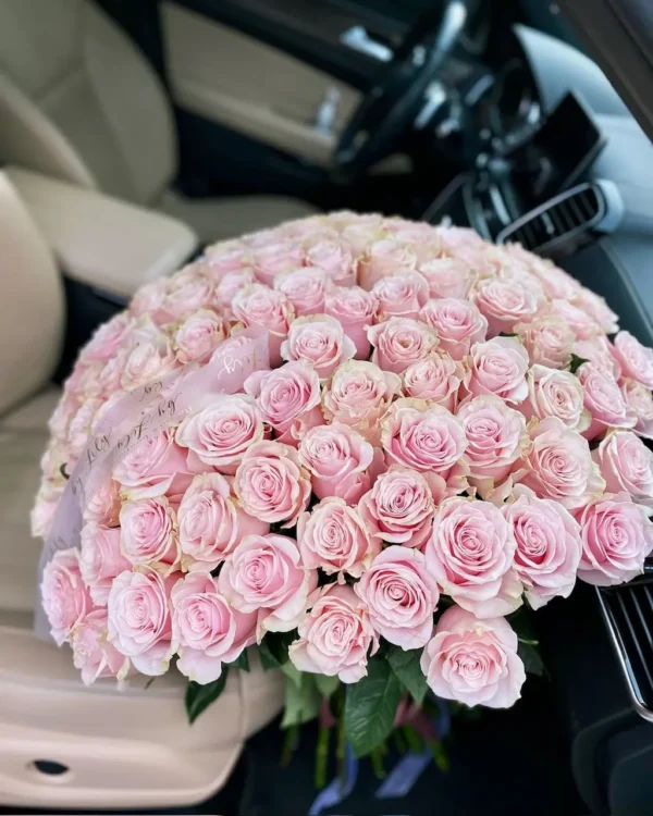 A large bouquet of pink roses elegantly arranged in the back seat of a car, adding a touch of beauty and romance.