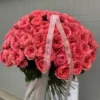 A woman gracefully holds a large bouquet of vibrant pink roses, showcasing their beauty and elegance.