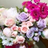 A vibrant bouquet of pink and purple flowers elegantly arranged in a clear glass vase, enhancing the room's decor.