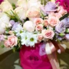 A vibrant bouquet of pink and purple flowers elegantly arranged in a clear glass vase, enhancing the room's decor.