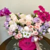 A vibrant bouquet of pink and purple flowers elegantly arranged in a clear glass vase, enhancing the room's decor.