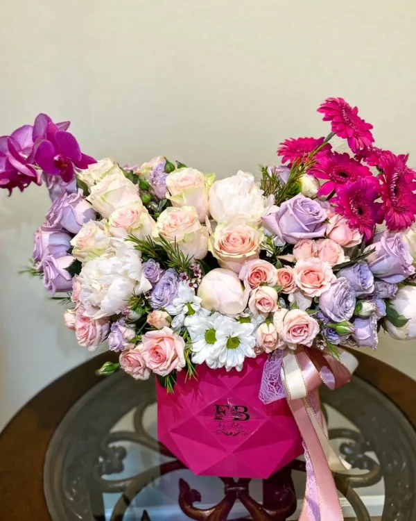 A vibrant bouquet of pink and purple flowers elegantly arranged in a clear glass vase, enhancing the room's decor.