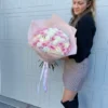 A woman gracefully holds a bouquet of pink and white roses, showcasing the beauty of the flowers in her hands.