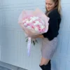 A woman gracefully holds a bouquet of pink and white roses, showcasing the beauty of the flowers in her hands.