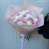 A woman gracefully holds a bouquet of pink and white roses, showcasing the beauty of the flowers in her hands.