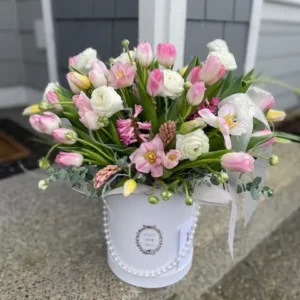 A white box filled with delicate pink and white flowers, creating a charming and elegant floral arrangement.