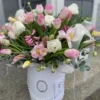 A white box filled with delicate pink and white flowers, creating a charming and elegant floral arrangement.