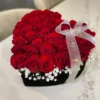 A heart-shaped box filled with vibrant red roses and delicate baby's breath, symbolizing love and affection.