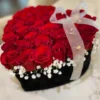 A heart-shaped box filled with vibrant red roses and delicate baby's breath, symbolizing love and affection.