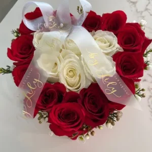 A heart-shaped arrangement featuring vibrant red and elegant white roses, symbolizing love and purity.