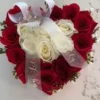 A heart-shaped arrangement featuring vibrant red and elegant white roses, symbolizing love and purity.