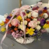 A beautifully arranged basket overflowing with vibrant flowers sits elegantly on a wooden table.