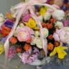 A beautifully arranged basket overflowing with vibrant flowers sits elegantly on a wooden table.