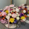 A beautifully arranged basket overflowing with vibrant flowers sits elegantly on a wooden table.