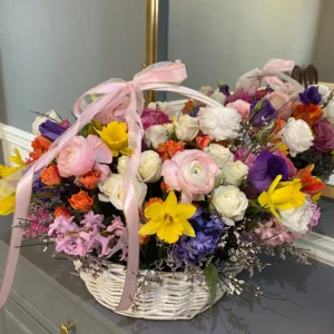 A beautifully arranged basket overflowing with vibrant flowers sits elegantly on a wooden table.