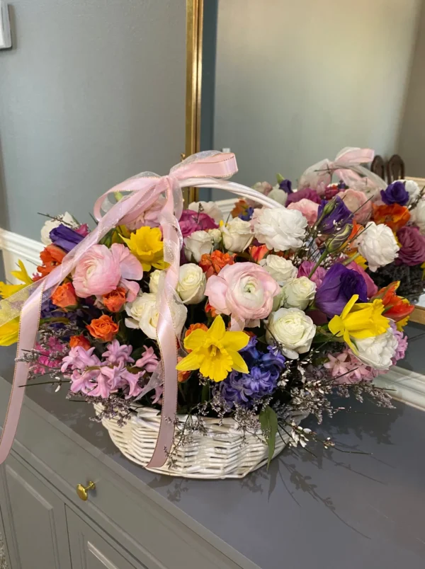 A beautifully arranged basket overflowing with vibrant flowers sits elegantly on a wooden table.