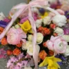 A beautifully arranged basket overflowing with vibrant flowers sits elegantly on a wooden table.