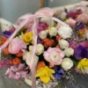 A beautifully arranged basket overflowing with vibrant flowers sits elegantly on a wooden table.