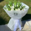 A bouquet of white tulips elegantly wrapped in clear plastic, showcasing their delicate petals and fresh appearance.