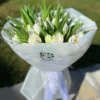 A bouquet of white tulips elegantly wrapped in clear plastic, showcasing their delicate petals and fresh appearance.