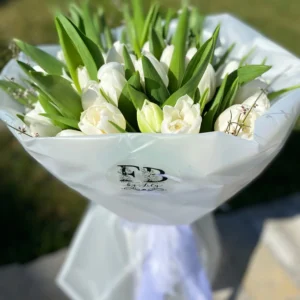 A bouquet of white tulips elegantly wrapped in clear plastic, showcasing their delicate petals and fresh appearance.