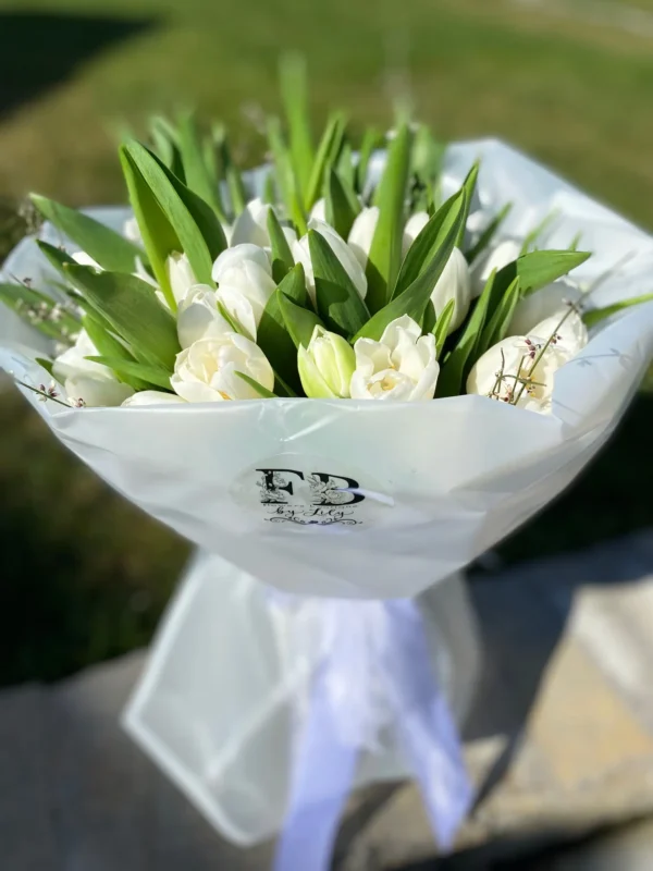 A bouquet of white tulips elegantly wrapped in clear plastic, showcasing their delicate petals and fresh appearance.