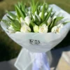 A bouquet of white tulips elegantly wrapped in clear plastic, showcasing their delicate petals and fresh appearance.