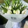 A bouquet of white tulips elegantly wrapped in clear plastic, showcasing their delicate petals and fresh appearance.