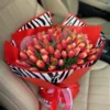 A vibrant bouquet of red and pink tulips elegantly tied with a stylish zebra print ribbon, showcasing a striking floral arrangement.