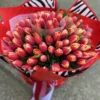 A vibrant bouquet of red and pink tulips elegantly tied with a stylish zebra print ribbon, showcasing a striking floral arrangement.