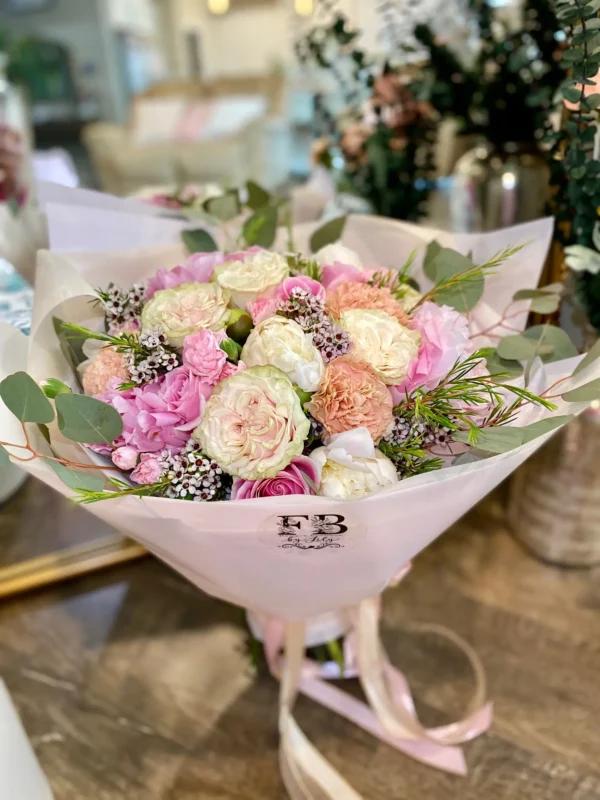 A lovely bouquet featuring pink and white flowers placed on a table, creating a serene and inviting atmosphere.