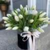 A bouquet of elegant white tulips arranged in a sleek black vase, showcasing a striking contrast of colors.