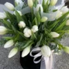 A bouquet of elegant white tulips arranged in a sleek black vase, showcasing a striking contrast of colors.