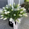 A bouquet of elegant white tulips arranged in a sleek black vase, showcasing a striking contrast of colors.