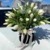 A bouquet of elegant white tulips arranged in a sleek black vase, showcasing a striking contrast of colors.