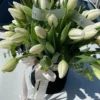 A bouquet of elegant white tulips arranged in a sleek black vase, showcasing a striking contrast of colors.