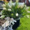 A bouquet of elegant white tulips arranged in a sleek black vase, showcasing a striking contrast of colors.