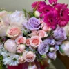 A vibrant bouquet of pink and purple flowers elegantly arranged in a clear glass vase, enhancing the room's decor.