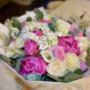 A vibrant bouquet of assorted flowers elegantly arranged in a simple white paper bag, showcasing natural beauty.