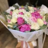 A vibrant bouquet of assorted flowers elegantly arranged in a simple white paper bag, showcasing natural beauty.