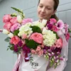 A woman gracefully holds a white box adorned with pink and white flowers, showcasing a delicate floral arrangement.