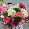 A woman gracefully holds a white box adorned with pink and white flowers, showcasing a delicate floral arrangement.