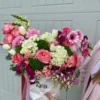 A woman gracefully holds a white box adorned with pink and white flowers, showcasing a delicate floral arrangement.