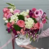 A woman gracefully holds a white box adorned with pink and white flowers, showcasing a delicate floral arrangement.