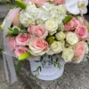 A white box adorned with delicate pink roses and elegant orchids, creating a charming floral arrangement.