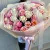 A woman gracefully holds a large bouquet of vibrant roses, showcasing their beauty and elegance in her hands.