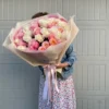 A woman gracefully holds a large bouquet of vibrant roses, showcasing their beauty and elegance in her hands.